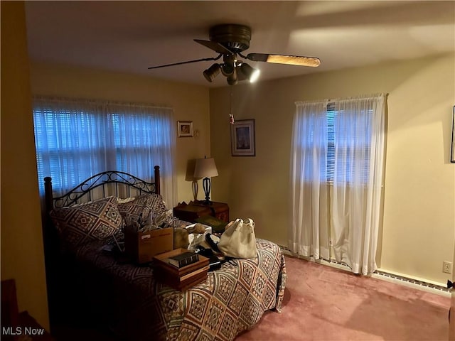 carpeted bedroom with ceiling fan and a baseboard heating unit