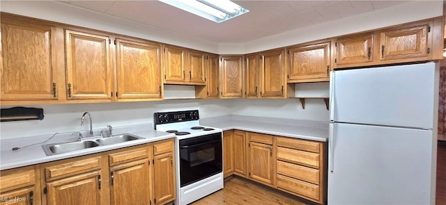 kitchen featuring light wood-type flooring, white appliances, sink, and a skylight