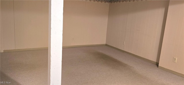 basement featuring light colored carpet and wooden walls