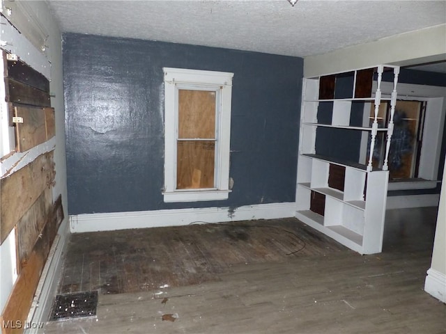 unfurnished room featuring dark hardwood / wood-style flooring and a textured ceiling