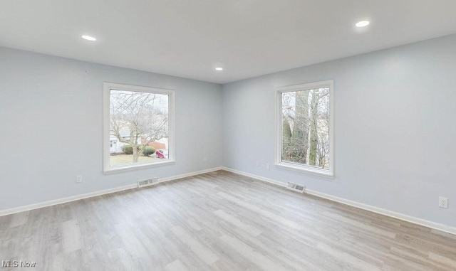 spare room featuring a wealth of natural light and light hardwood / wood-style flooring