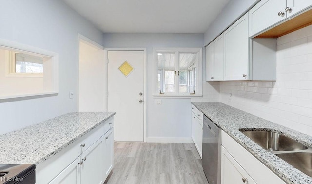 kitchen featuring decorative backsplash, stainless steel dishwasher, sink, white cabinets, and light hardwood / wood-style floors