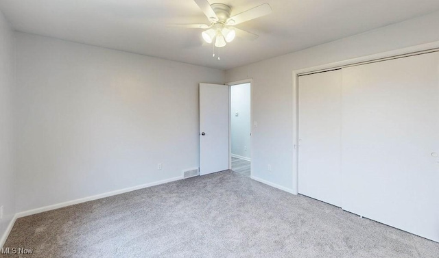 unfurnished bedroom featuring ceiling fan, light colored carpet, and a closet