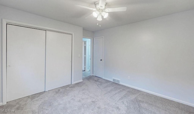 unfurnished bedroom with ceiling fan, light colored carpet, and a closet