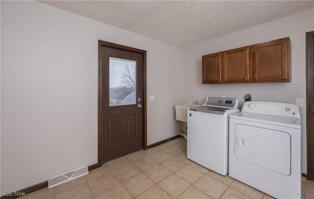 laundry area featuring cabinets, sink, washer and dryer, a textured ceiling, and light tile patterned flooring