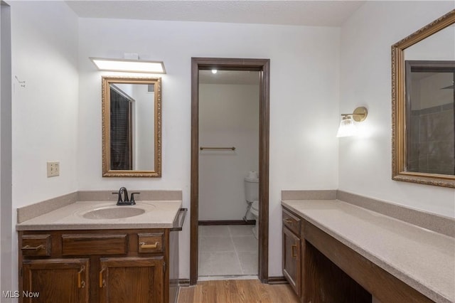 bathroom featuring wood-type flooring, vanity, and toilet