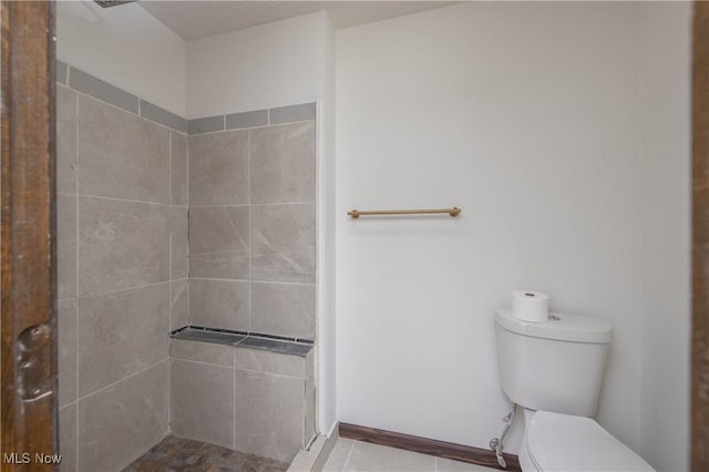 bathroom featuring a tile shower and toilet