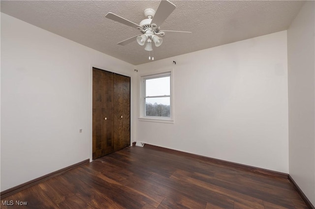 empty room with ceiling fan, dark wood-type flooring, and a textured ceiling