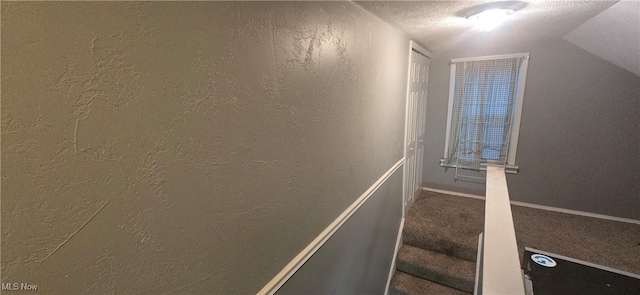 staircase with lofted ceiling, a textured ceiling, and carpet floors