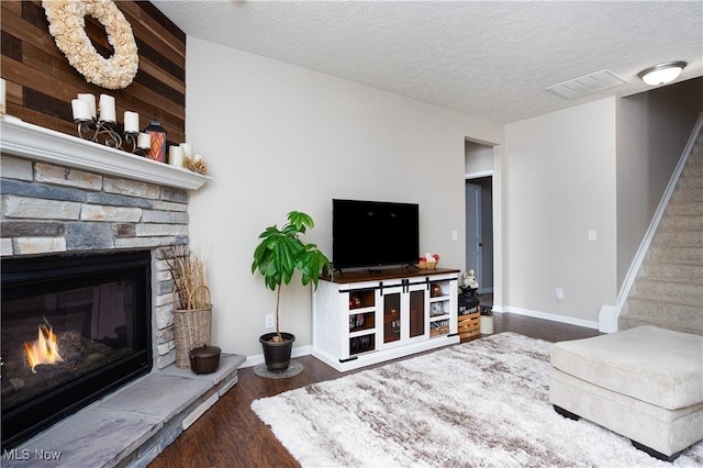 living room with a fireplace, dark hardwood / wood-style flooring, and a textured ceiling