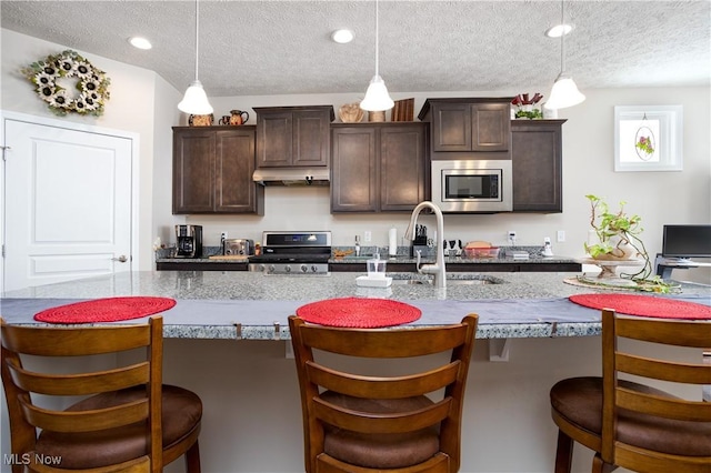 kitchen featuring dark brown cabinets, hanging light fixtures, and appliances with stainless steel finishes