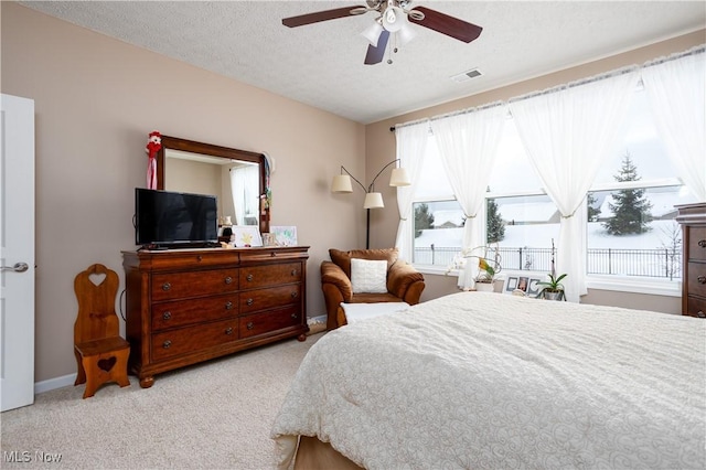 carpeted bedroom featuring ceiling fan and a textured ceiling