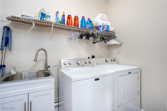 clothes washing area with washer and dryer, cabinets, and sink