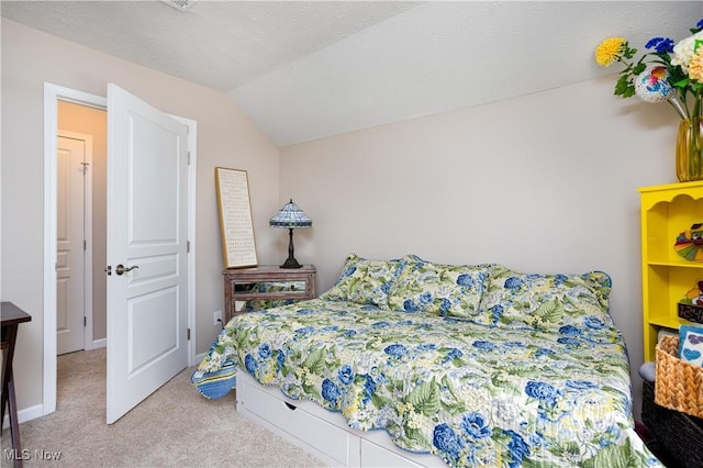 carpeted bedroom with a textured ceiling and vaulted ceiling