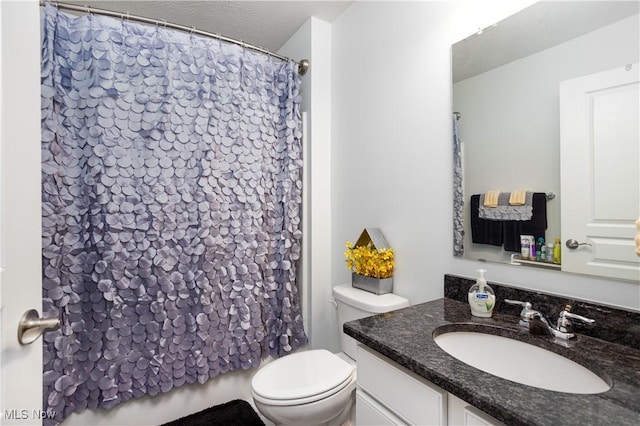 bathroom with vanity, curtained shower, toilet, and a textured ceiling