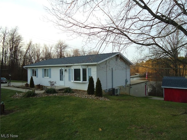 view of front of property featuring a front lawn, central AC unit, and a storage unit