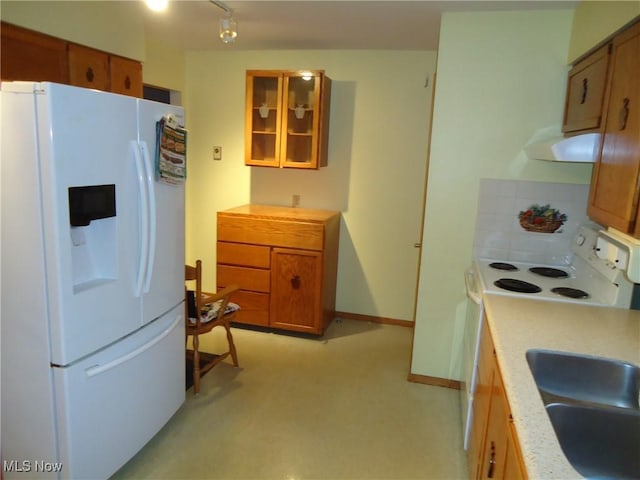 kitchen featuring white appliances, sink, and range hood