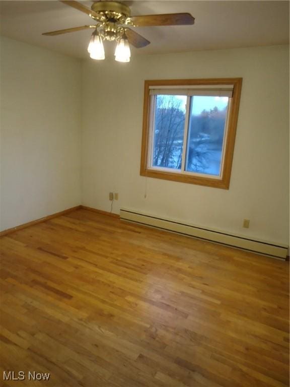 spare room featuring ceiling fan, light wood-type flooring, and baseboard heating