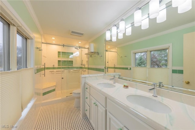 bathroom featuring toilet, vanity, a shower with shower door, and ornamental molding