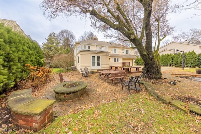 rear view of house with a patio area, a balcony, and an outdoor fire pit