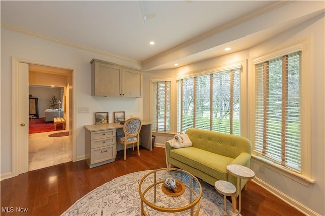 sitting room featuring crown molding, a wealth of natural light, dark hardwood / wood-style flooring, and built in desk