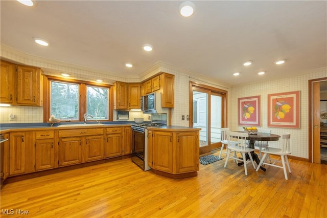 kitchen with kitchen peninsula, light hardwood / wood-style floors, gas range oven, and ornamental molding