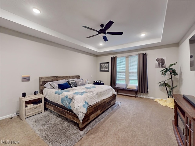 bedroom featuring a raised ceiling, ceiling fan, and light colored carpet