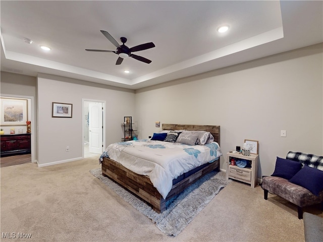 carpeted bedroom with a raised ceiling and ceiling fan