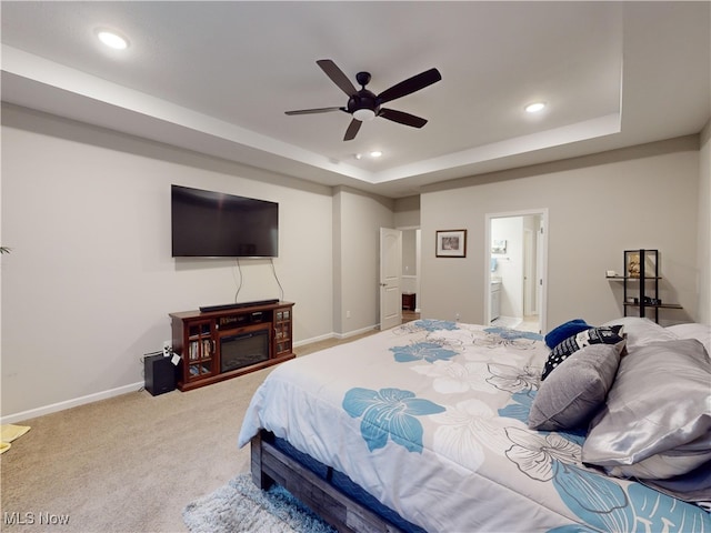 carpeted bedroom with ceiling fan, a raised ceiling, and connected bathroom