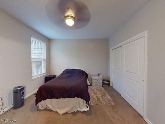 carpeted bedroom with ceiling fan and a closet