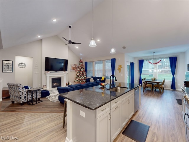 kitchen with white cabinets, a kitchen island with sink, sink, and a wealth of natural light