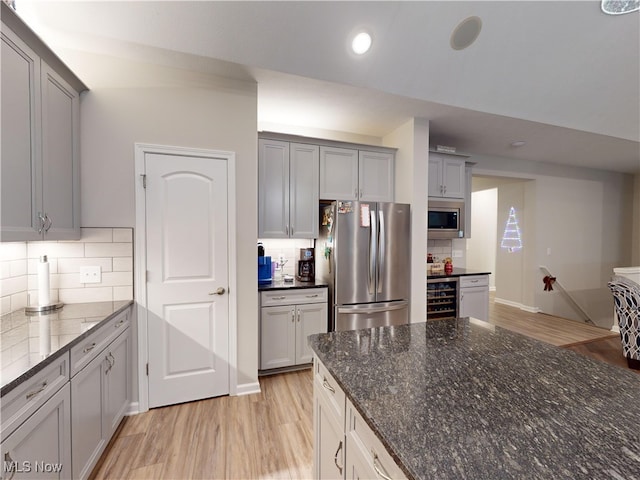 kitchen with wine cooler, decorative backsplash, stainless steel appliances, and light wood-type flooring