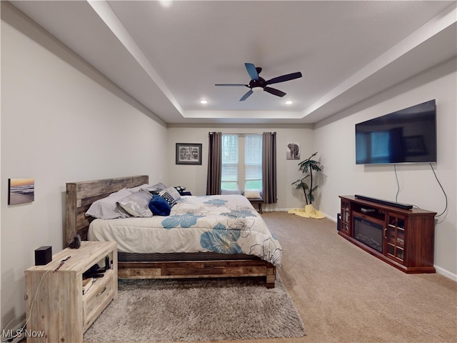 carpeted bedroom featuring a raised ceiling and ceiling fan