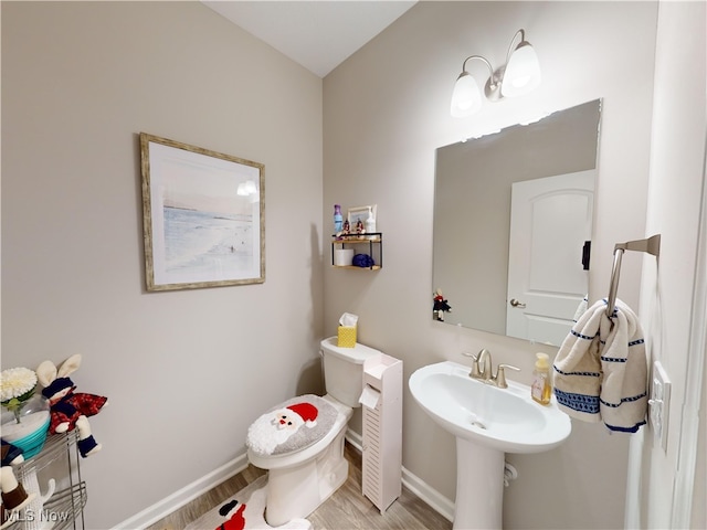 bathroom with wood-type flooring, toilet, and sink