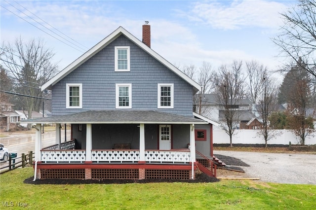 rear view of house featuring a porch and a yard