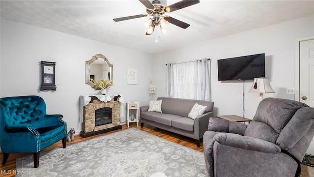 living room with a fireplace, ceiling fan, and hardwood / wood-style floors