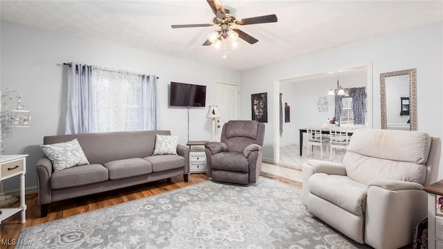 living room featuring ceiling fan with notable chandelier and hardwood / wood-style flooring