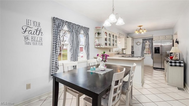 dining area featuring light tile patterned floors, sink, and an inviting chandelier