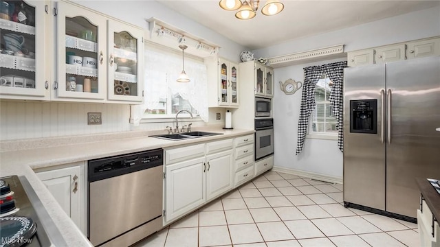 kitchen featuring white cabinetry, sink, stainless steel appliances, decorative light fixtures, and light tile patterned floors