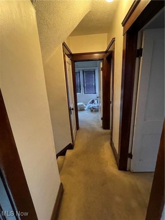 hallway with light carpet and a textured ceiling