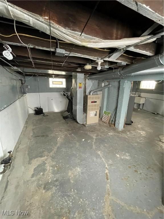 basement with plenty of natural light, sink, and heating unit