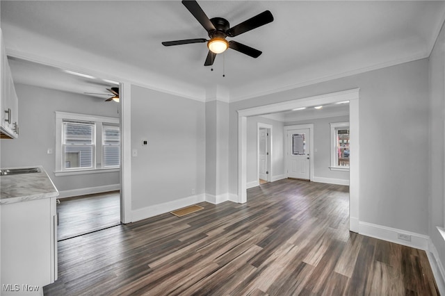 unfurnished living room with dark hardwood / wood-style floors, ceiling fan, and crown molding