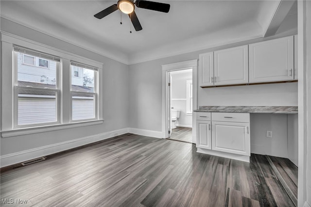 kitchen with dark hardwood / wood-style flooring, ceiling fan, built in desk, and white cabinetry