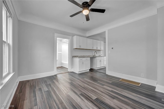 unfurnished living room with dark hardwood / wood-style floors, ceiling fan, and sink