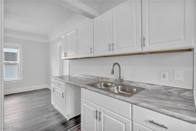 kitchen with light stone countertops, white cabinetry, sink, and dark wood-type flooring