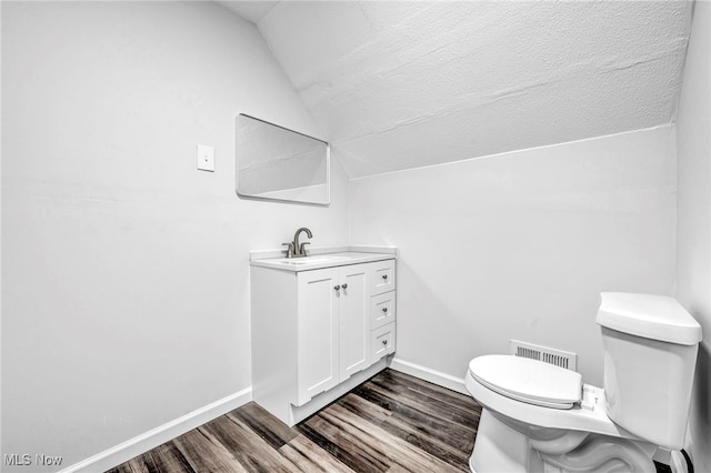 bathroom featuring vanity, lofted ceiling, hardwood / wood-style flooring, toilet, and a textured ceiling