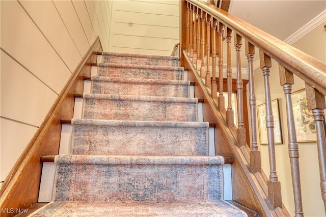 staircase with wooden walls and ornamental molding