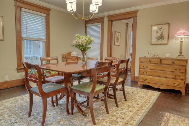 dining space with crown molding, dark wood-type flooring, and an inviting chandelier