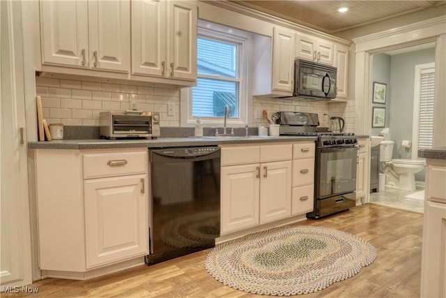 kitchen with white cabinets, tasteful backsplash, light hardwood / wood-style flooring, and black appliances