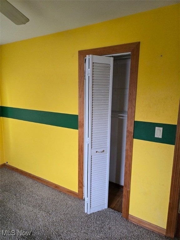 unfurnished bedroom featuring a closet and dark colored carpet